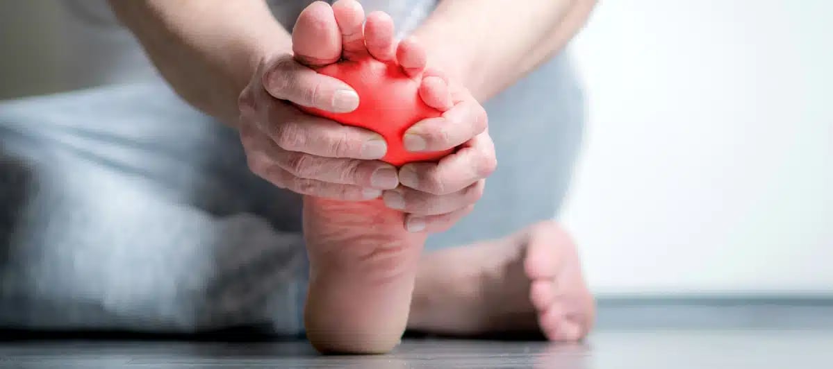 a person with neuropathy holds his painful feet